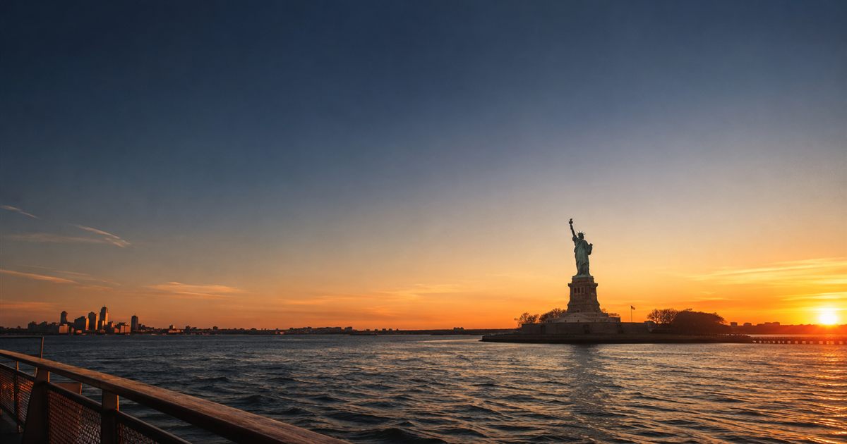 La Statue de la Liberté au coucher du soleil vue depuis la baie de New York, illustration de l'article sur les voies d'accès à la Green Card